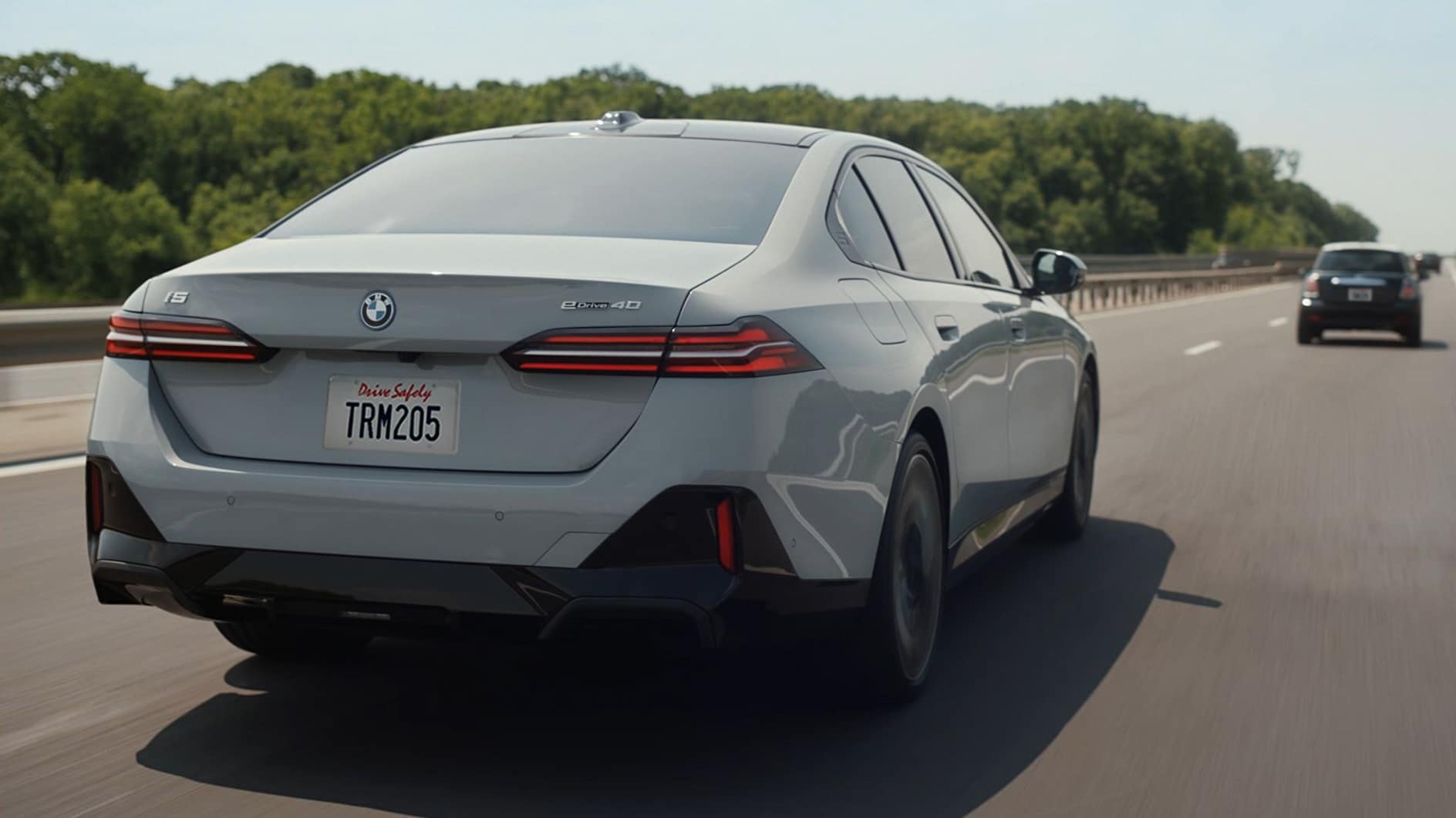 A rear view of a white BMW i5 driving down the highway. A rear view of a white BMW i5 driving down the highway.