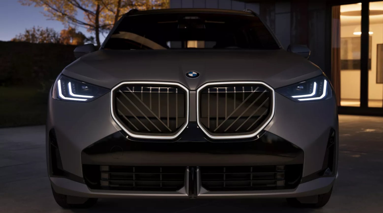 Front view of a dark grey BMW X3 at night.