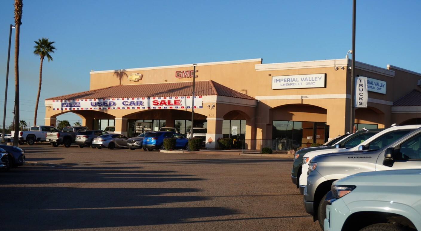 exterior shot of Imperial Valley GMC, in summer, at sunset, with new and used GMC vehicles parked out front