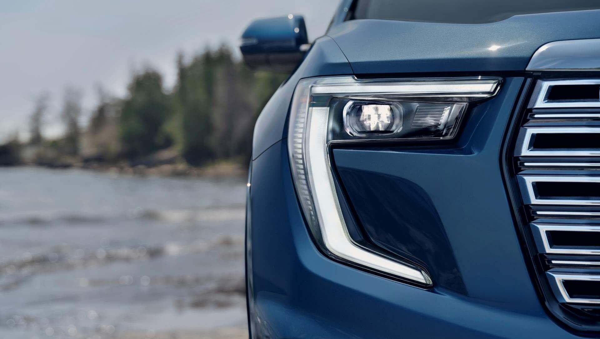 Closeup of headlight of GMC Acadia in rainy background