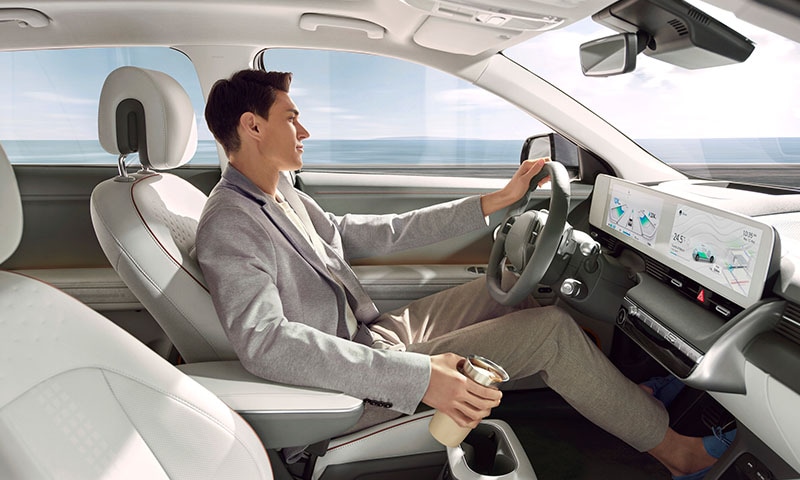All-New 2023 Hyundai Ioniq 5 at Jack Giambalvo Hyundai | View From Passenger Side Window Looking in at Man Driving 2022 Hyundai Ioniq 5 while REaching for Coffee Cup | Photos of 2023 Hyundai Ioniq 5 Coming Soon