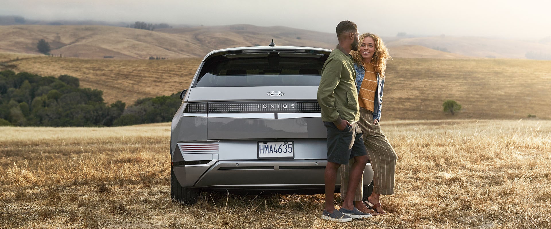 All-New 2023 Hyundai Ioniq 5 at Jack Giambalvo Hyundai | Couple Talking and Leaning Against Back of 2022 Hyundai Ioniq 5 in Middle of Field | Photos of 2023 Hyundai Ioniq 5 Coming Soon