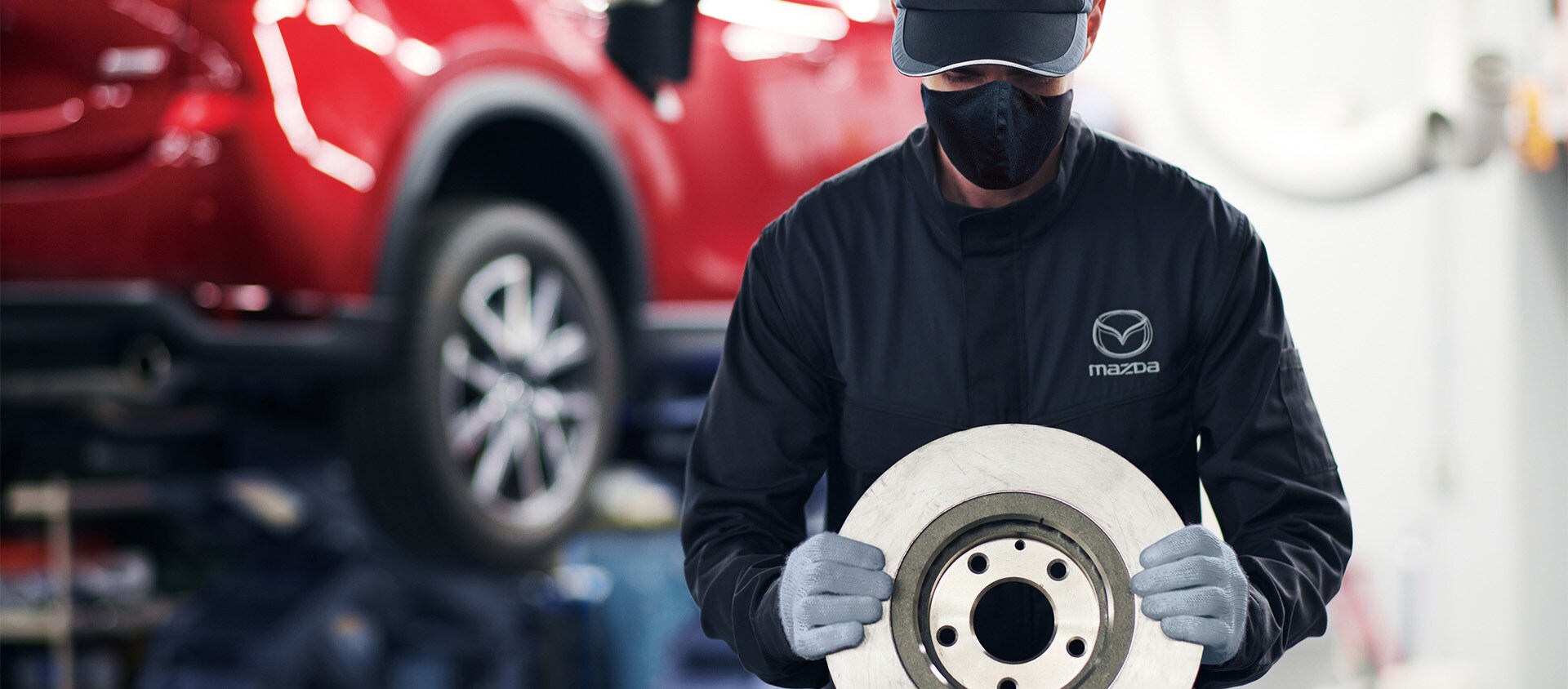 Brake replacement and Safety at Jack Giambalvo Mazda | Mazda Service Advisor Holding Brake While Standing in Service Bay