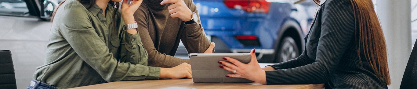 Vehicle Registration Taxes and Fees at Jack Giambalvo Mazda in York, PA | Sales person on the right is showing a couple on the left details of vehicle registration with an iPad