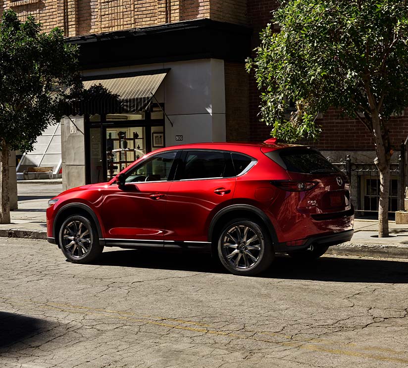 Model Features of the 2021 Mazda CX-5 at Jack Giambalvo Mazda | Profile Shot of Red 2021 Mazda CX-5 Street Parked in City