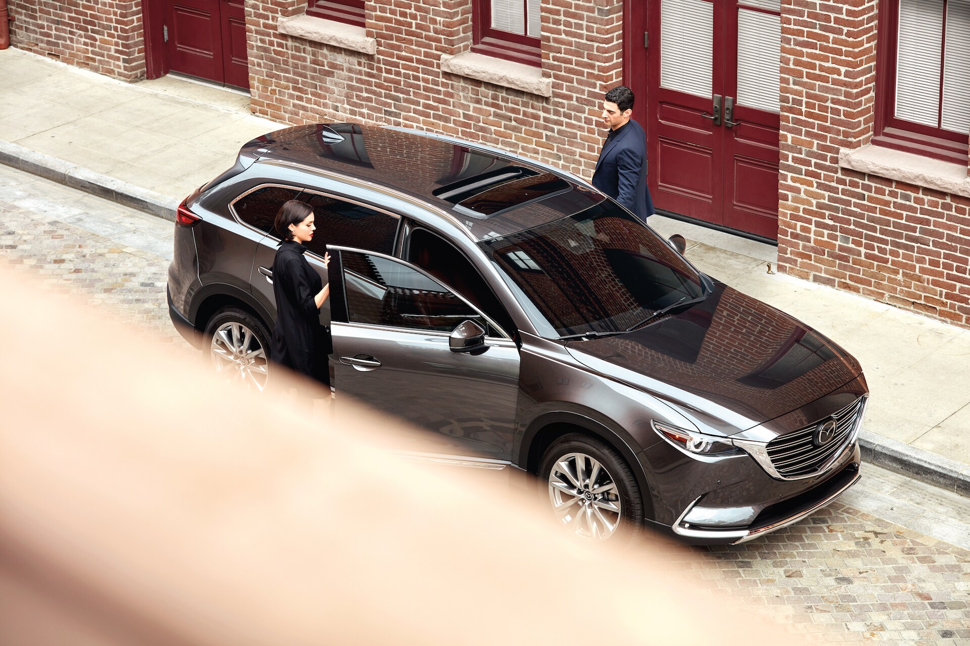 Jack Giambalvo Mazda is a Car Dealership in York PA | High angle view of well-dressed couple entering 2020 Mazda CX-9 in city street