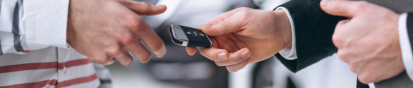 Vehicle Registration Taxes and Fees at Jack Giambalvo Mazda in York, PA | Man in black suit on the right is handing over black new car keys to a man in white shirt on the left 