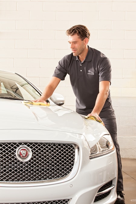 Jaguar service tech washing car after appointment
