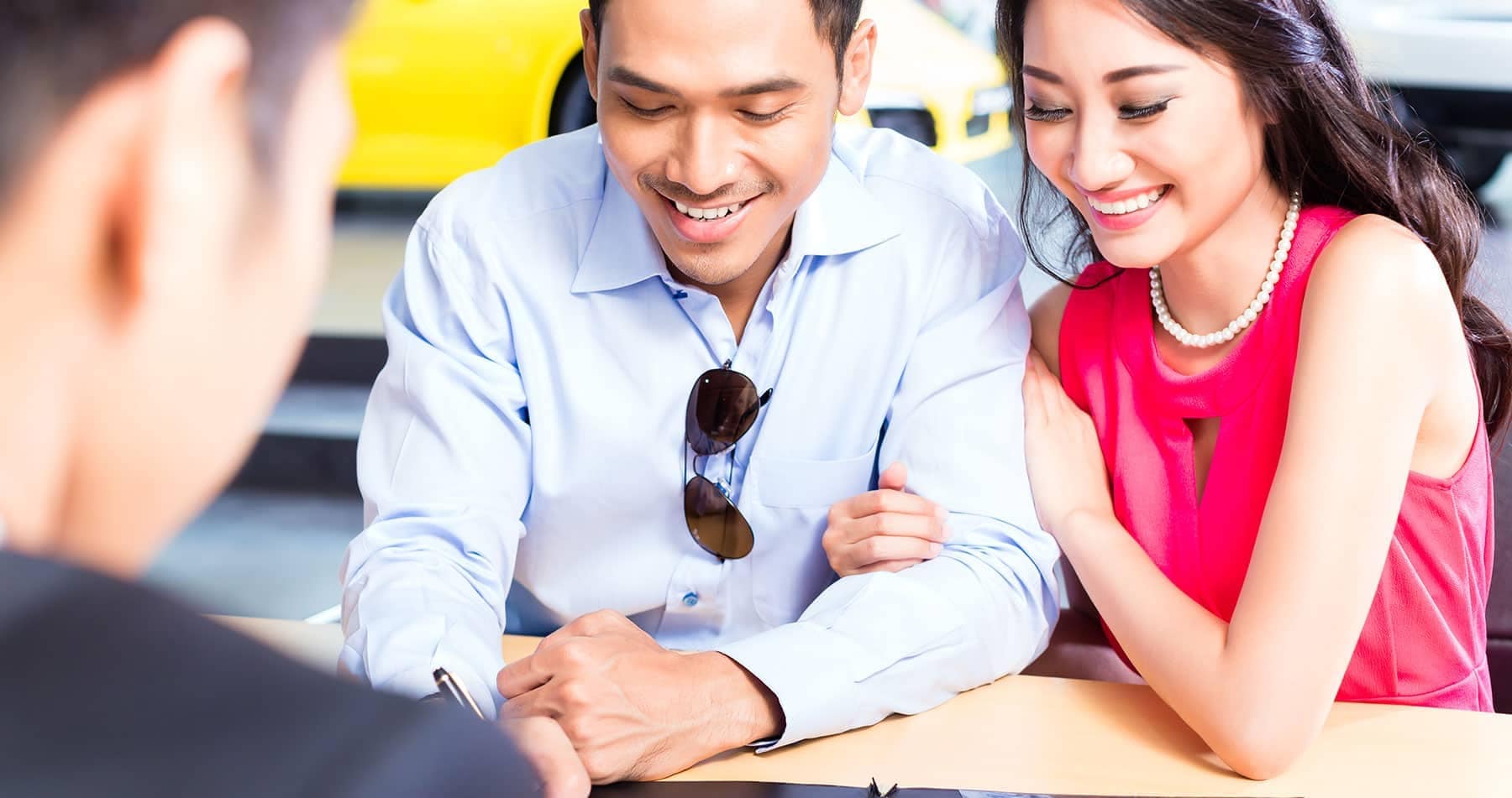 a smiling couple while signing financial paperwork