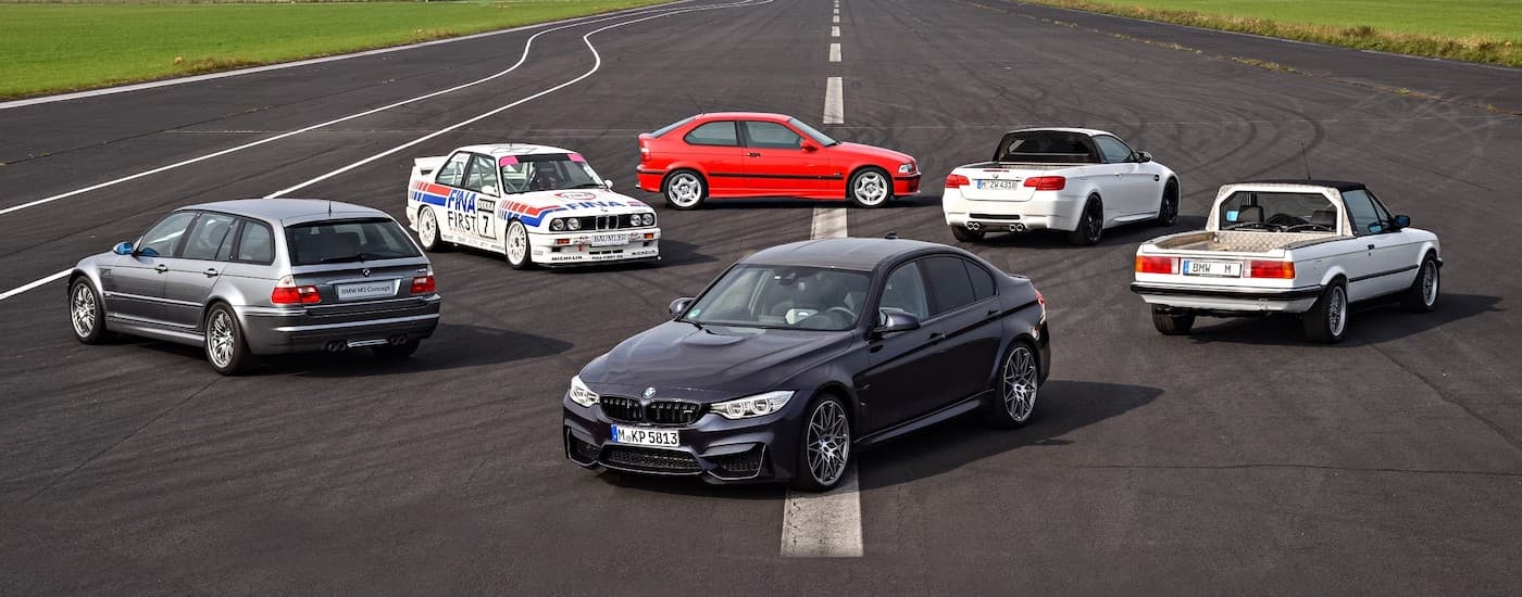 A 2020 BMW M3 is shown on a runway with older model M3s in the background.