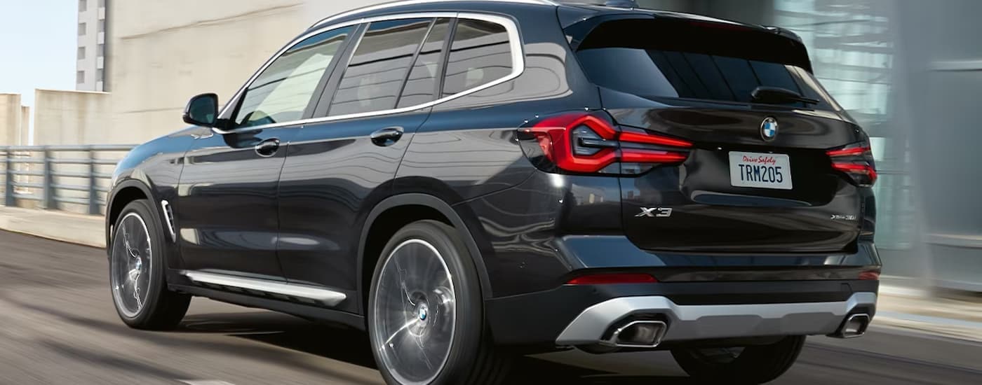 A black 2023 BMW X3 is shown driving up an on-ramp towards a freeway.