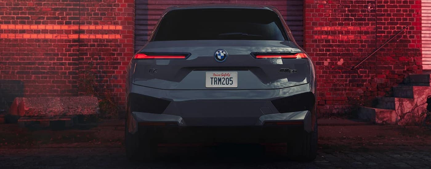 A grey 2022 BMW iX M60 is shown from behind parked in front of a brick wall.