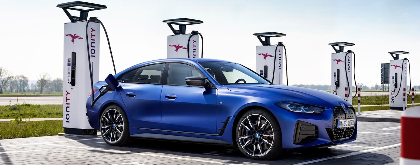 A blue 2022 BMW i4 M50 is shown from the side parked at a charging station.