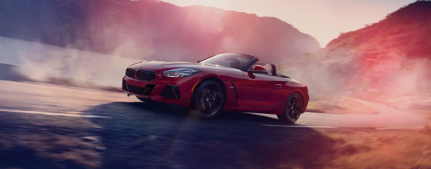 A red 2021 BMW Z4 convertible is driving on a winding road past mist.