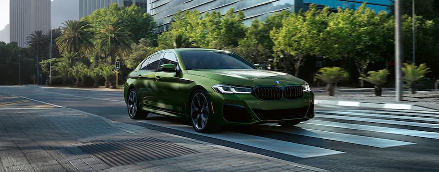A green 2022 BMW 5 Series is shown speeding down a city street.