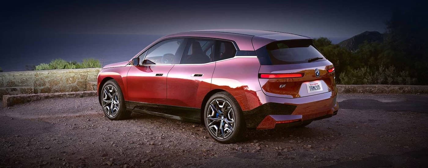 A red 2024 BMW iX is shown from the rear at an angle.