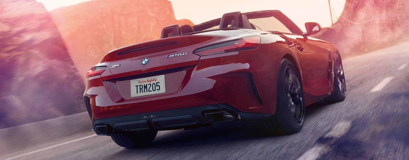 A red 2022 BMW Z4 M40i is shown driving on a road from behind.
