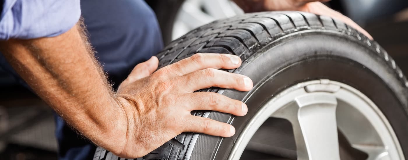 A closeup shows hands rolling a tire.