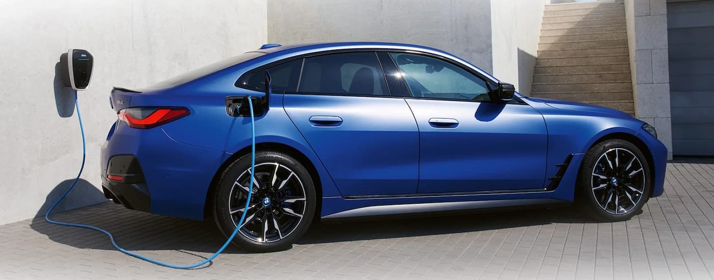 A blue 2022 BMW i4 is shown from the side charging.