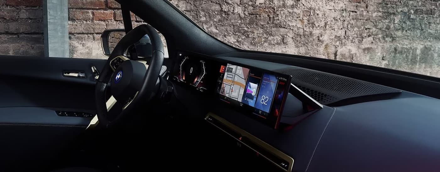 The blue interior of a 2024 BMW iX is shown from the pasenger side.