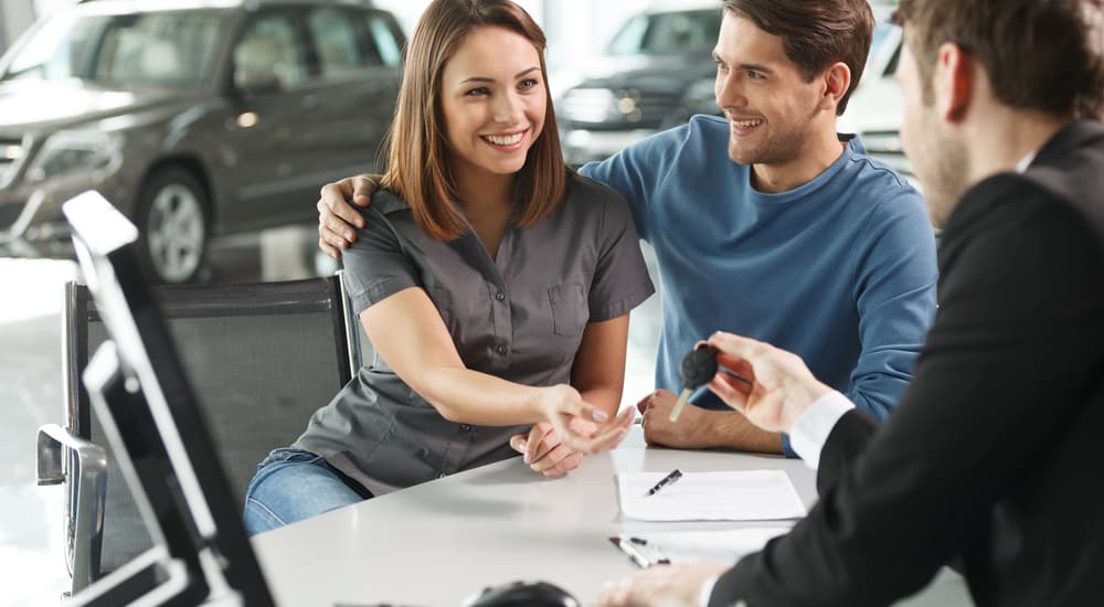 A couple is shown speaking to a salesman about trading in their vehicle.