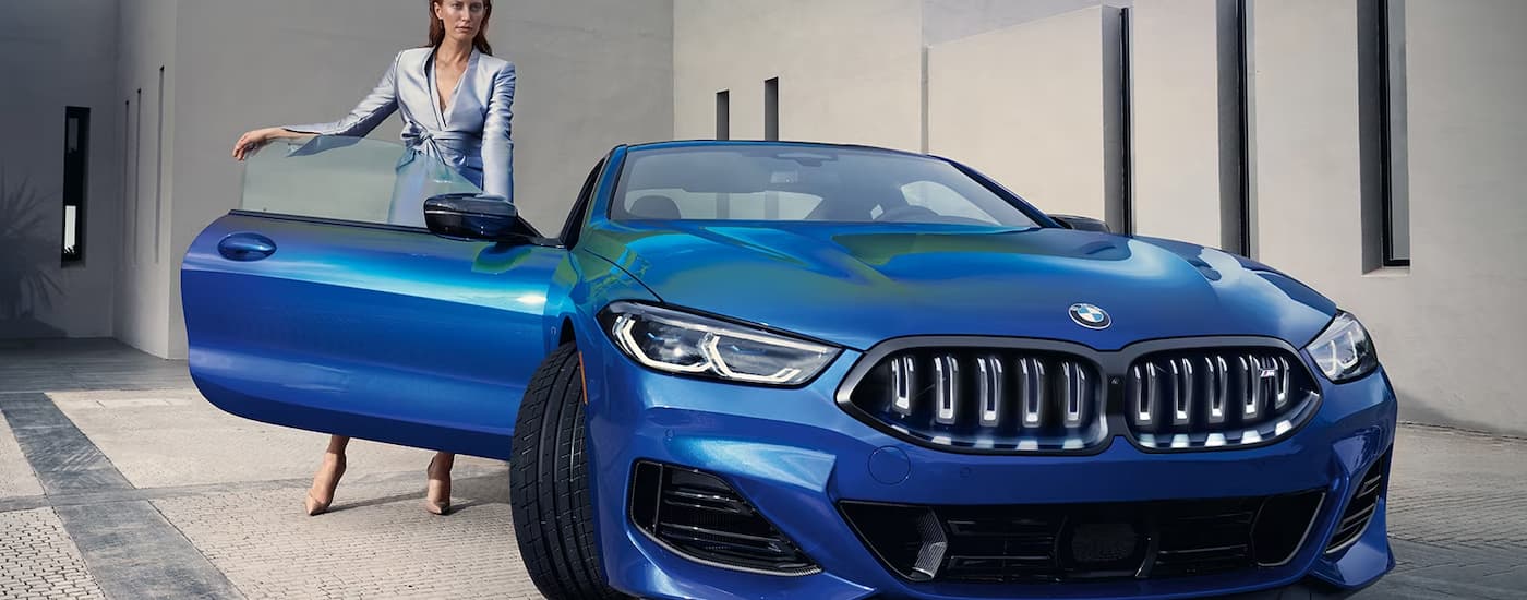 A woman is shown getting out of the passenger side of a blue 2023 BMW 8 Coupe.