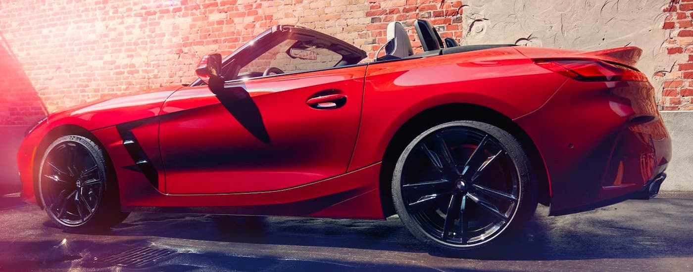 A red 2020 BMW Z4 convertible roadster is parked in front of a brick wall and shown from the side.