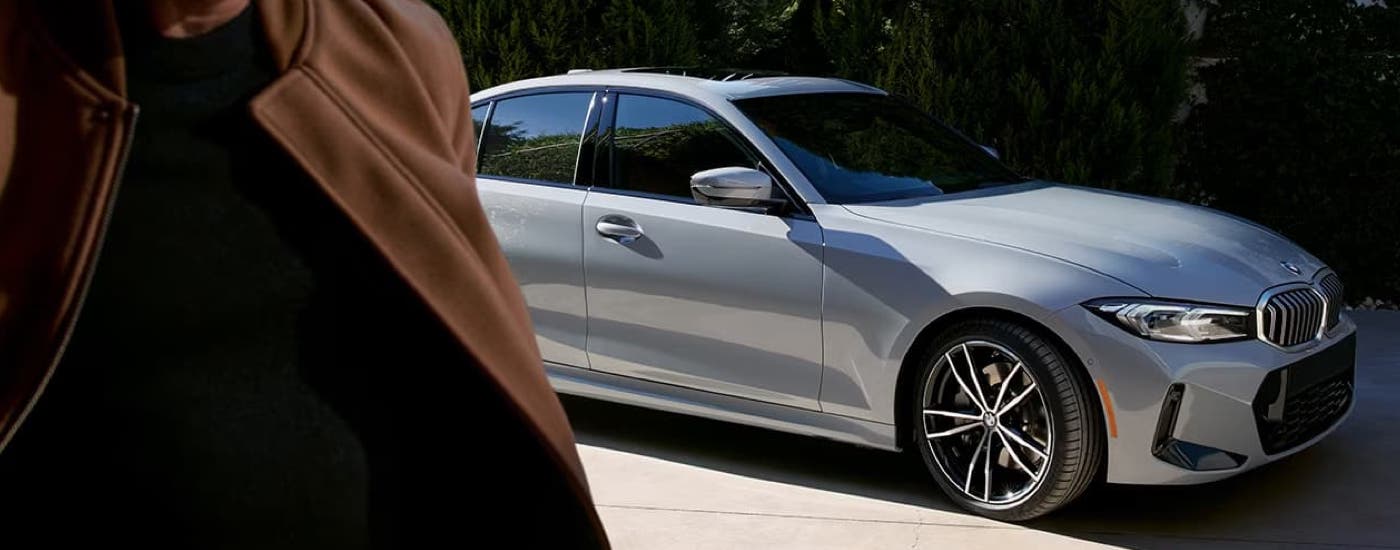 A grey 2023 BMW 3-Series is shown parked on a concrete driveway.