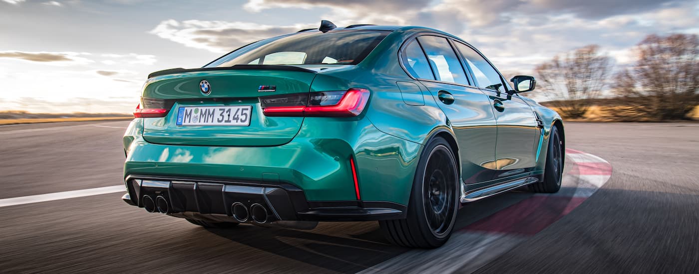 A green 2022 BMW M3 Competition is shown from the rear driving on a race track.