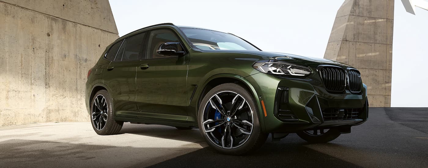 A green 2023 BMW X3 M4O0i is shown parked in a garage. class=