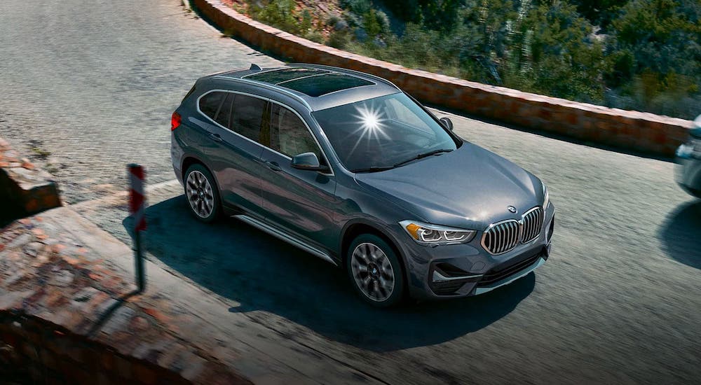 A gray 2019 BMW X1 is driving on a cobblestone road after leaving a used BMW dealer near you.