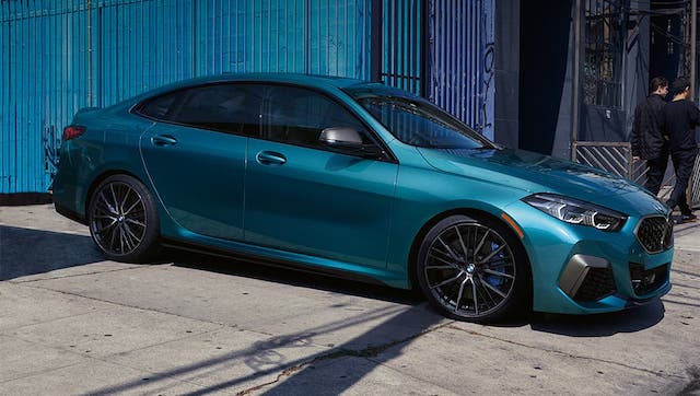 A teal 2020 BMW 2 Series Gran Coupe is parked in front of shipping containers.