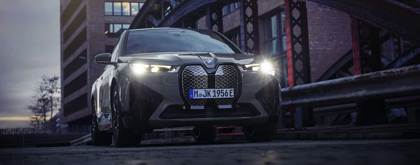 A grey 2022 BMW iX M60 is shown driving over a bridge in a city after visiting a Springdale BMW dealer.