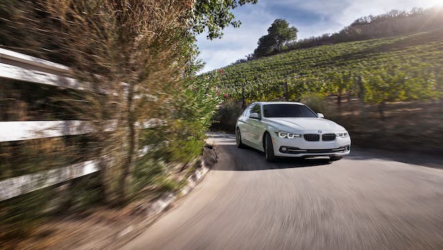 A white 2020 BMW 3 Series is driving through a vineyard.
