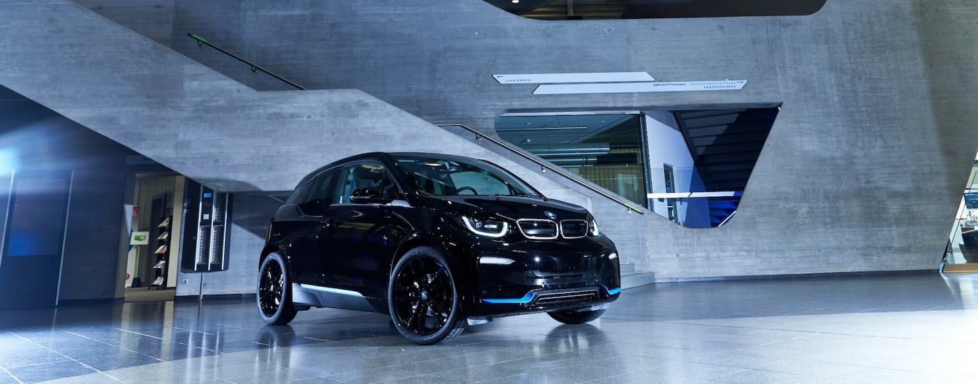 A black 2021 BMW i3 is shown from the side parked in a modern lobby.