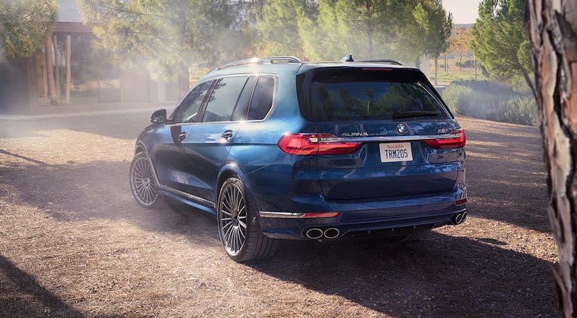 A blue 2020 BMW X7 Alpina is parked in front of a modern home.