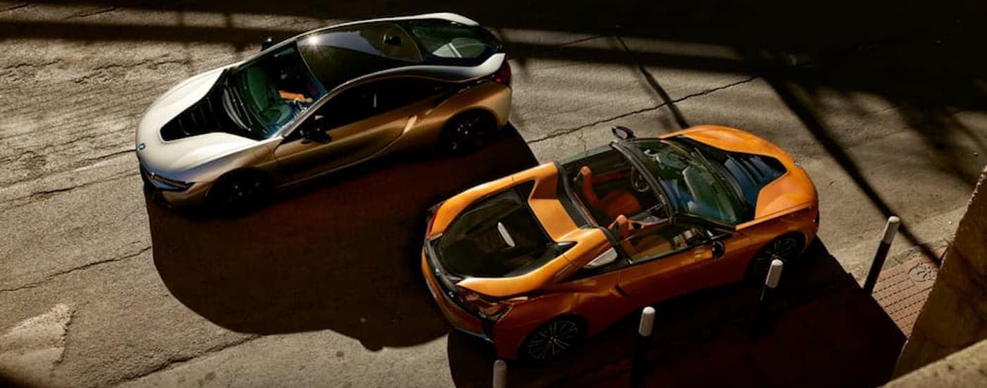 A white and an orange 2020 BMW i8 are shown from above.
