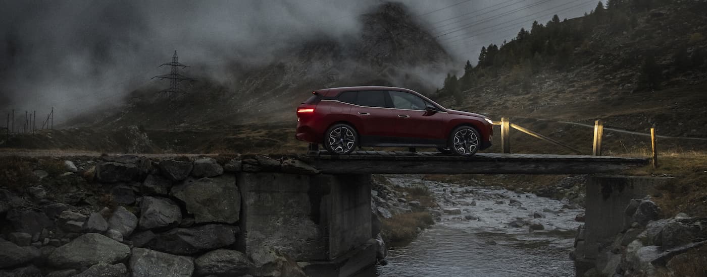 A maroon 2022 BMW iX is shown driving over a bridge after visting a Sharonville BMW dealership.