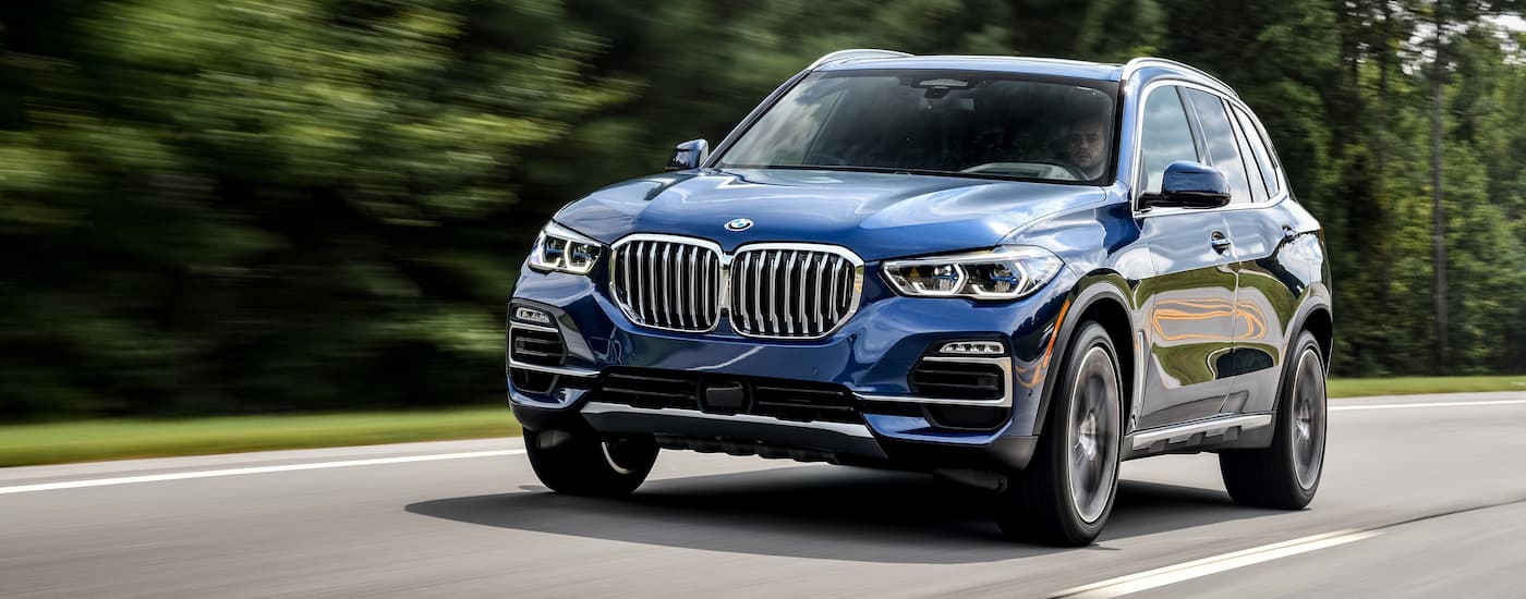A blue 2018 BMW X5 is shown driving on an open road.