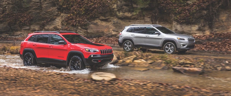 2019 Jeep Cherokee A red and a silver Cherokee offroading in a creek