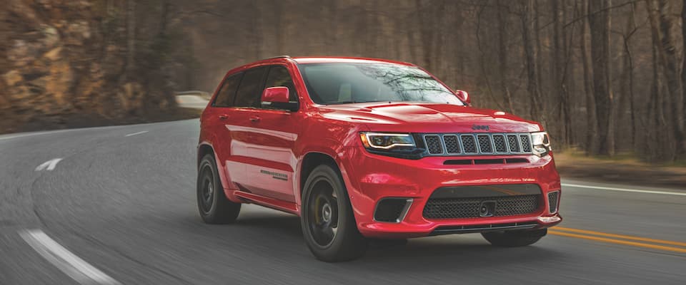A red 2019 Jeep Grand Cherokee driving down an open road