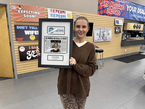 Jordan Malone-Forst holding her CBT News 40 Under 40 Class of 2026 plaque inside Jay Malone Motors in Hutchinson, MN