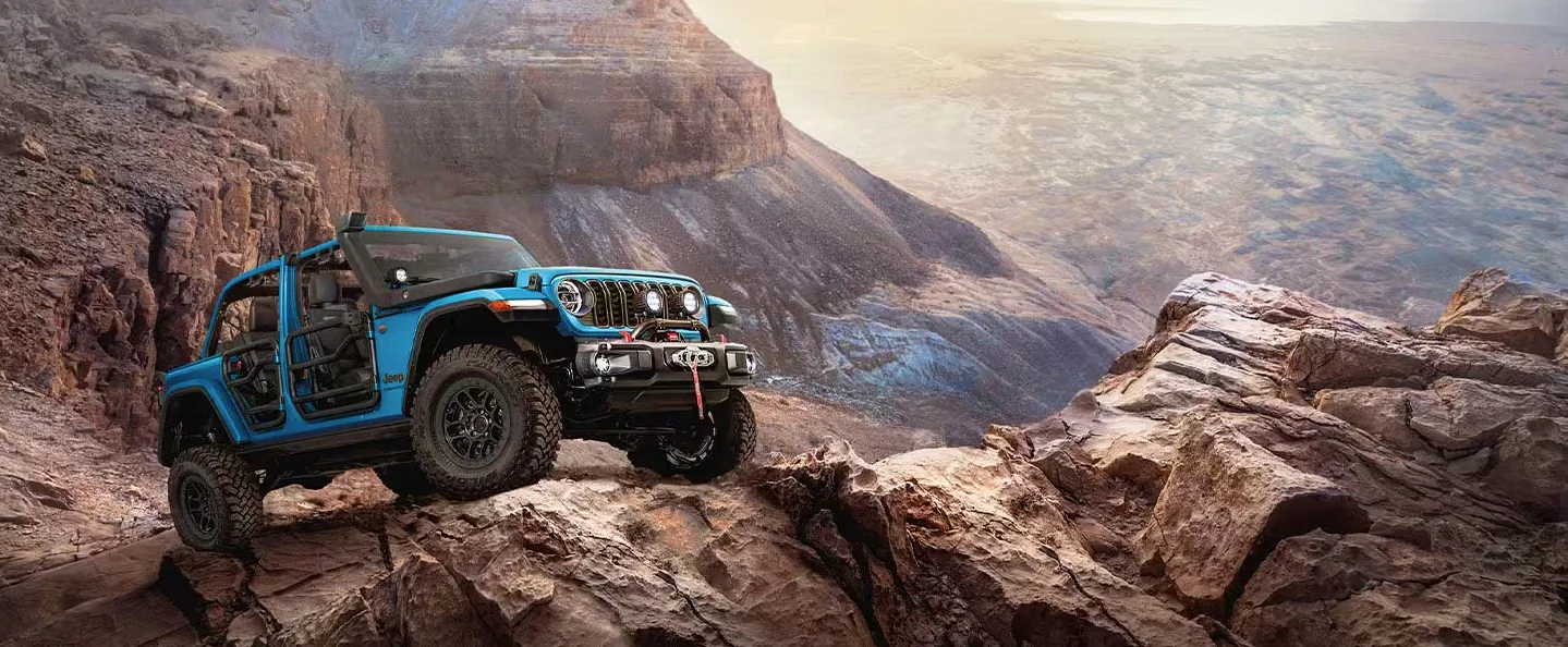 Blue Jeep Wrangler climbing rocky terrain with doors removed for adventure