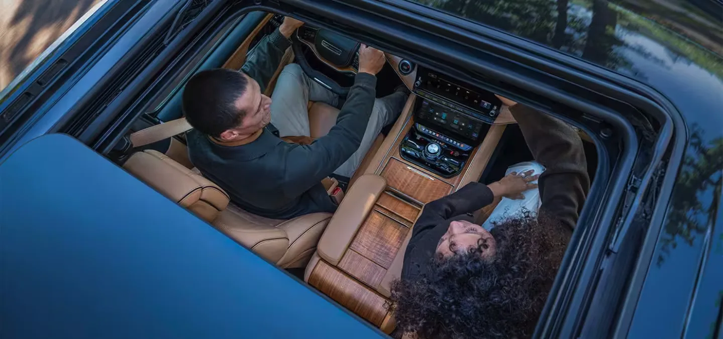 Overhead view of a Jeep Grand Wagoneer interior with two occupants using the center touchscreen