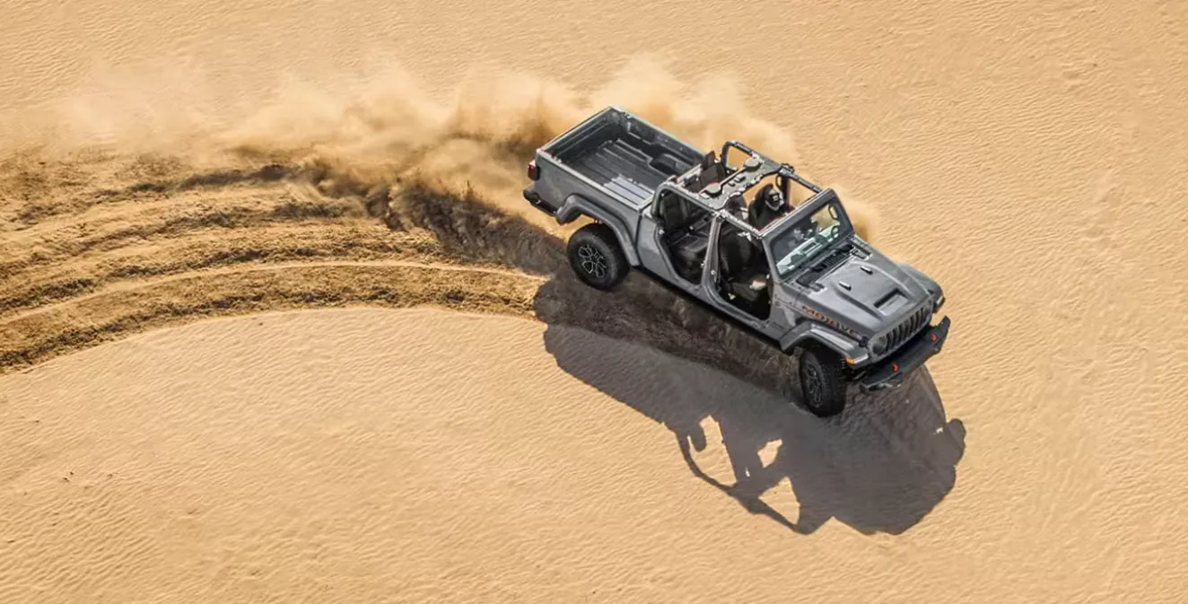 Jeep Gladiator pickup kicking up sand during off-road driving near Las Vegas