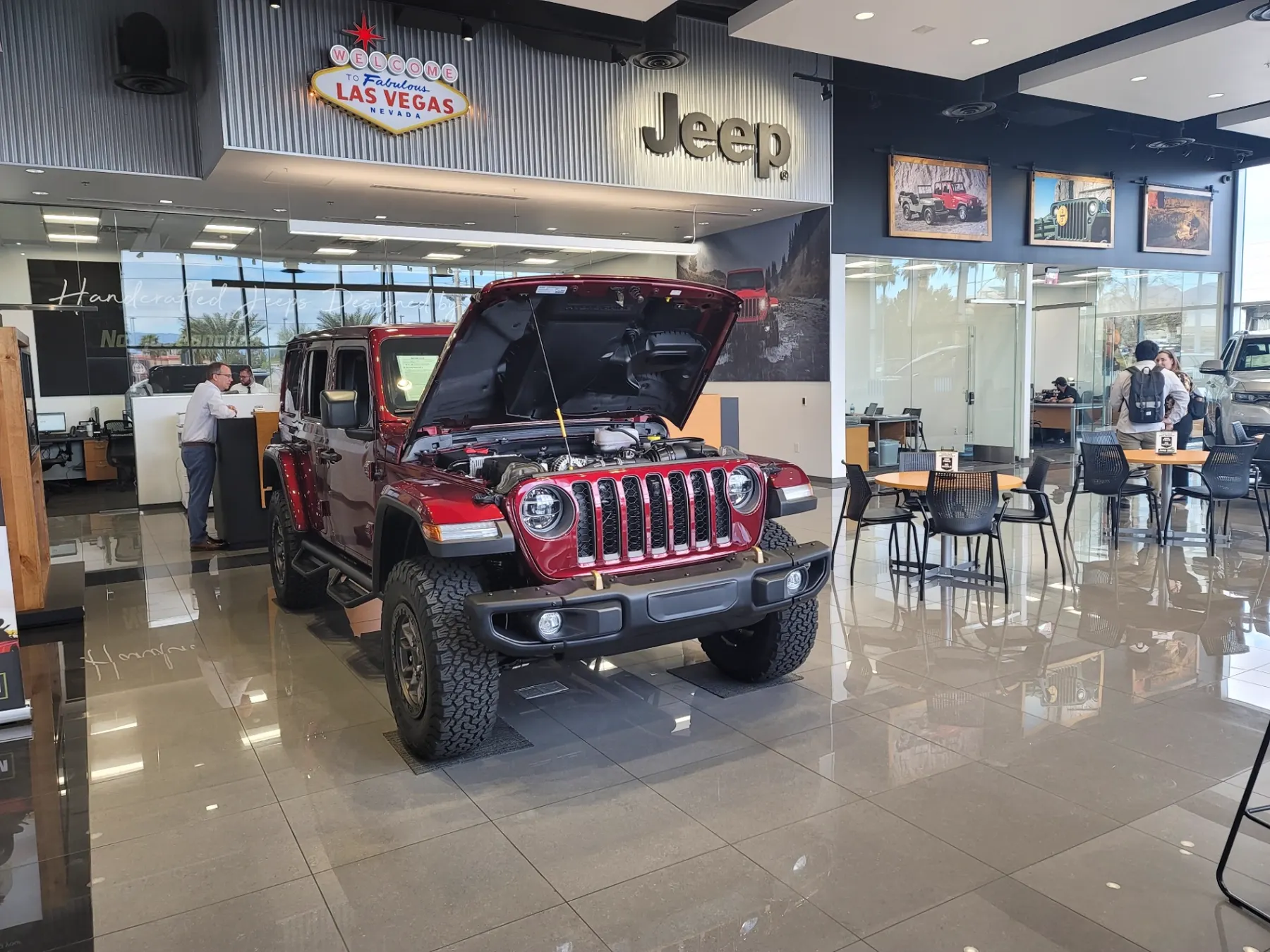 Red Jeep Wrangler Rubicon with the hood open on the Jeep Only showroom floor while a shopper speaks with a product specialist
