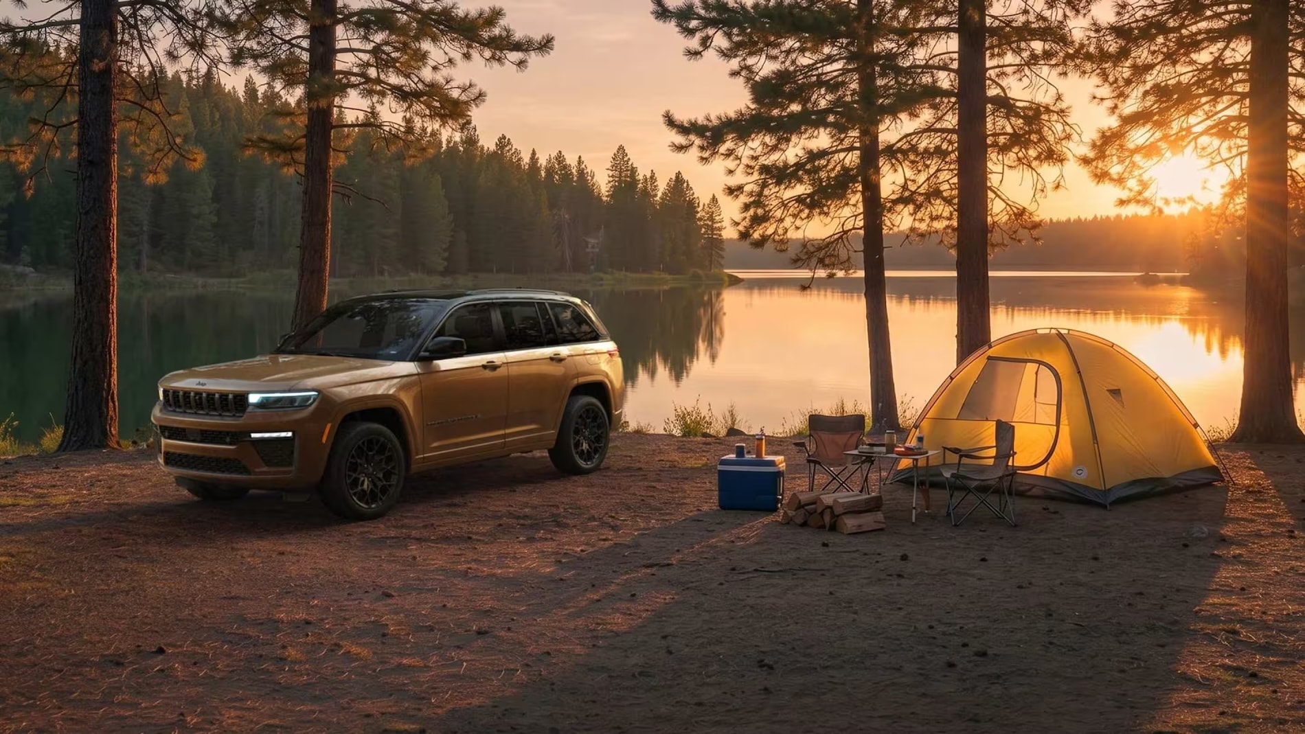 Gold 2027 Jeep Grand Cherokee parked at a lakeside campsite at sunset