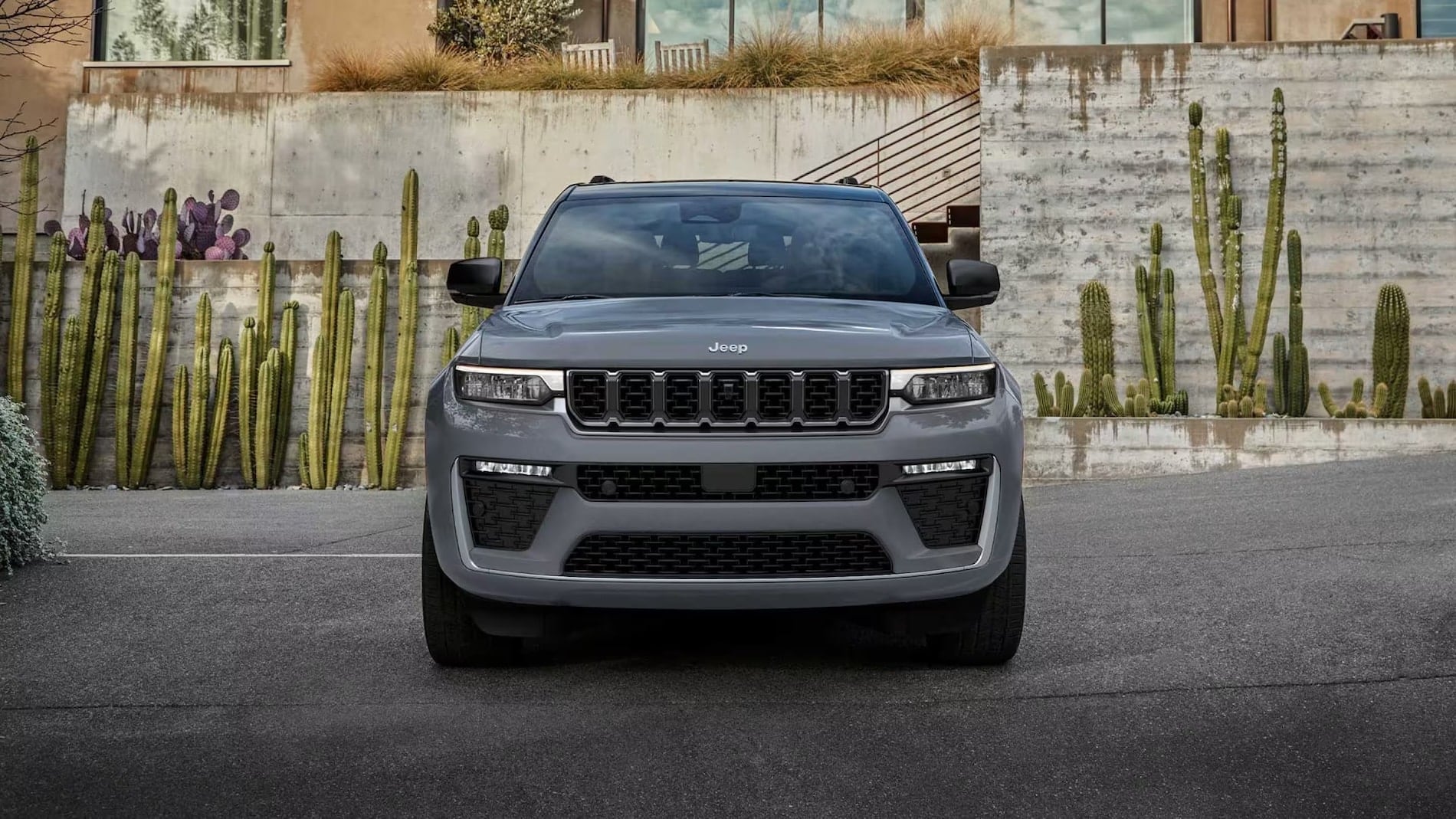 Gray 2027 Jeep Grand Cherokee shown head-on in a desert driveway