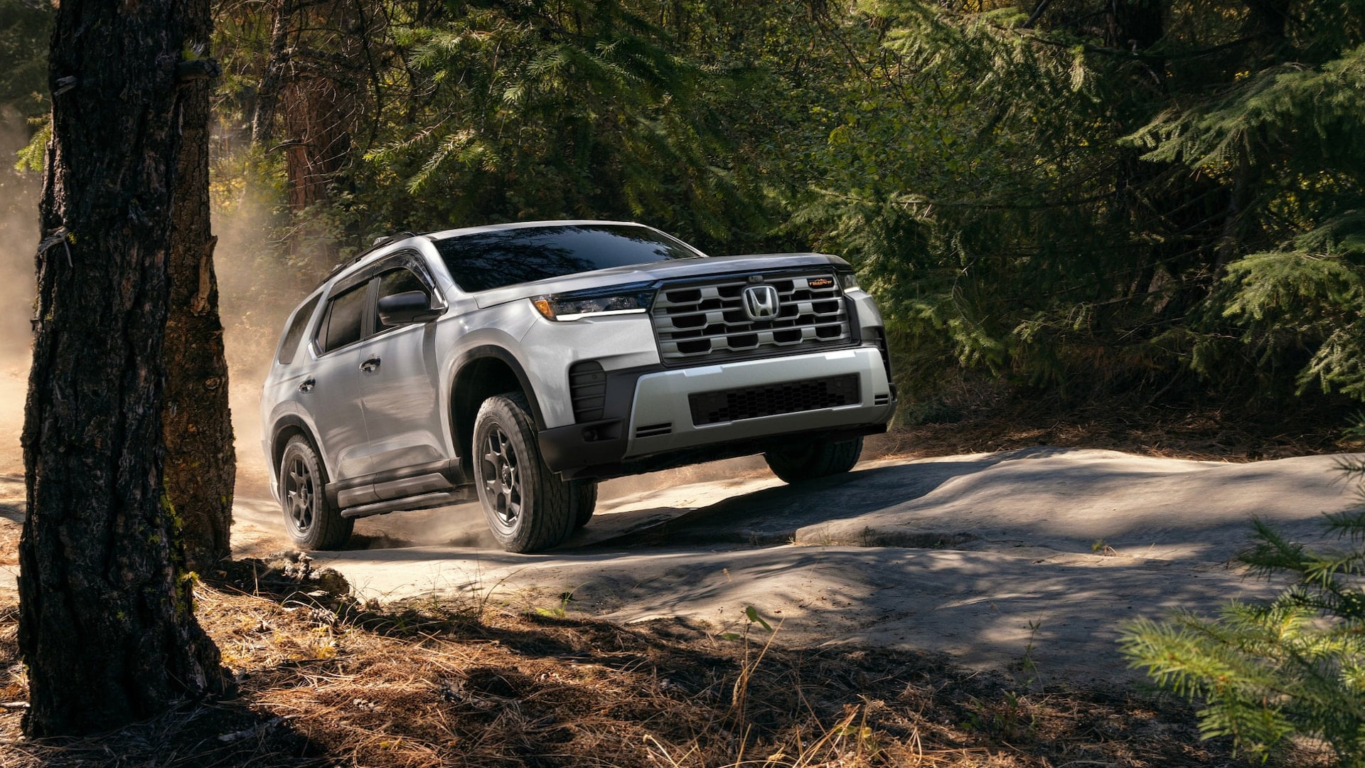 A white Honda Pilot driving on a bumpy trail in a forest