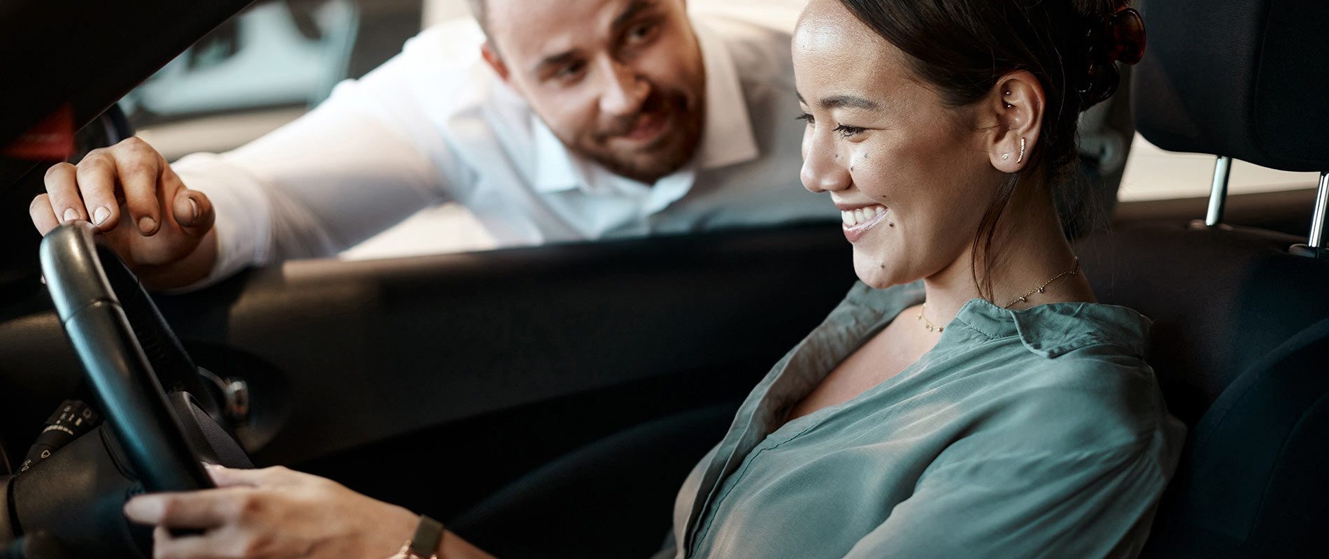 Pre-Owned Cars, Trucks, & SUVs for Sale in Florida A woman behind the wheel of a car as a salesman looks through the window inside a dealership.